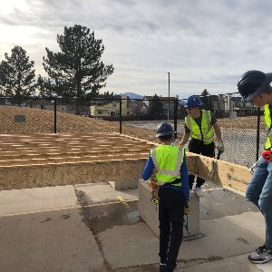 Three students work of the floor framing of a new house.